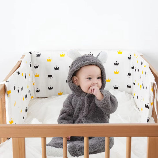 bebe assis dans son lit avec tour de lit bebe