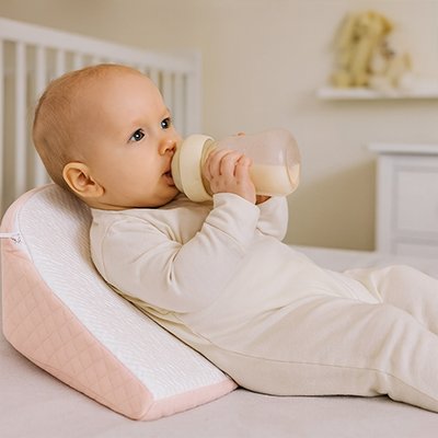 Bébé avec biberon sur oreiller de pense pour bébé