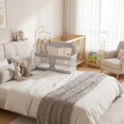 berceau pliable gris sur le cote de lit parents