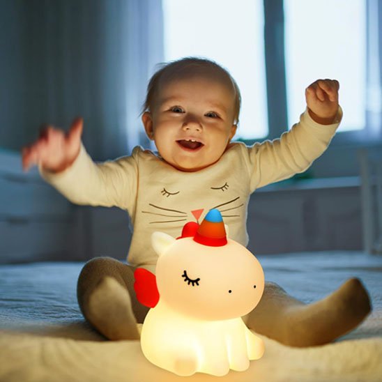 bebe assis souriant avec sa veilleuse bebe
