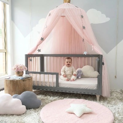 bebe assit sourit sous ciel de lit pour berceau-bebe