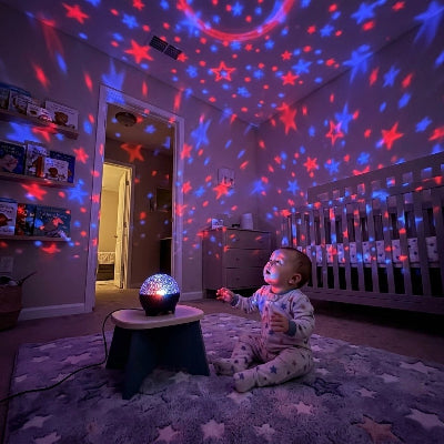 Bébé assit sous veilleuse bébé projecteur allumée