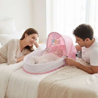 bebe dans berceau pliable entre maman papa