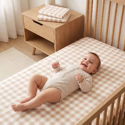 Bébé heureux sur son lit avec drap housse enfant
