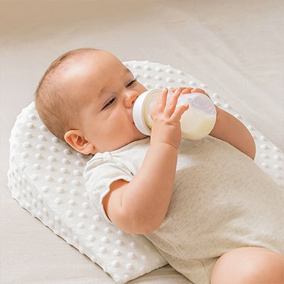 Bébé tient biberon sur oreiller pour bébé