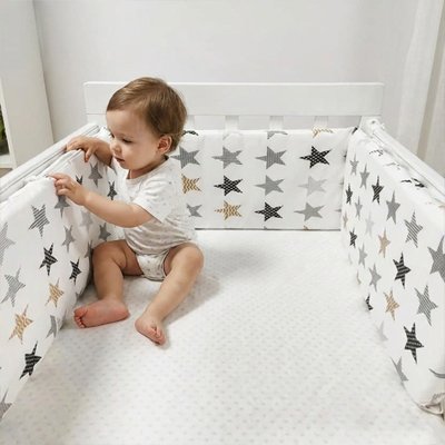 Garçon assit dans lit couvert du tour de lit bébé 