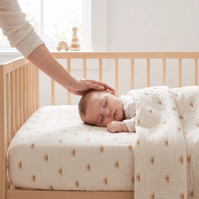 Maman berce bébé couche sur drap housse bébé