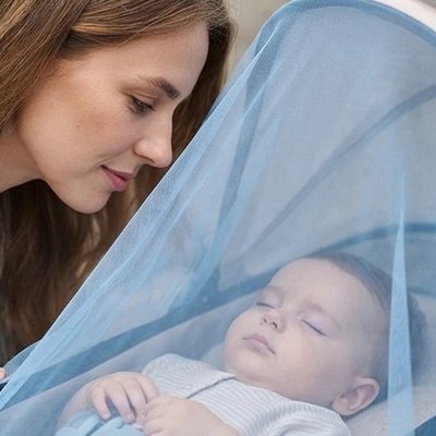 Maman regarde bébé dort sous moustiquaire poussette​