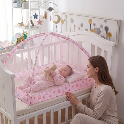maman surveille bébé couché dans moustiquaire lit bébé 