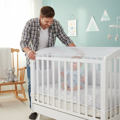 Papa regardant bébé par la moustiquaire lit bébé